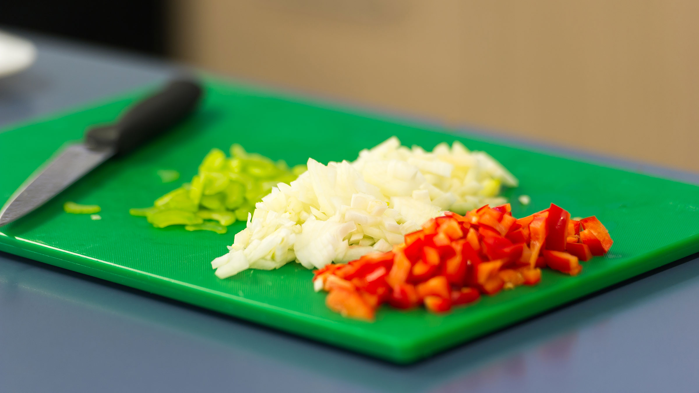 A chopping board with sliced celery, onions and capsicum
