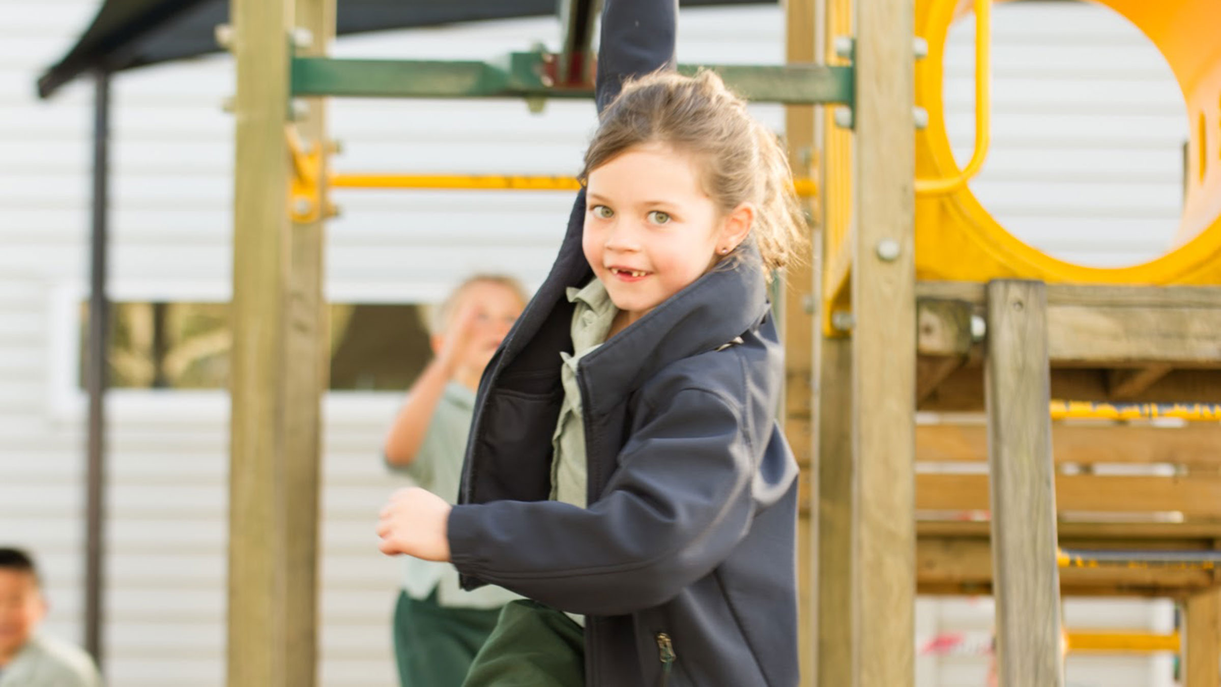 A young girl swinging on the bars in a playground.