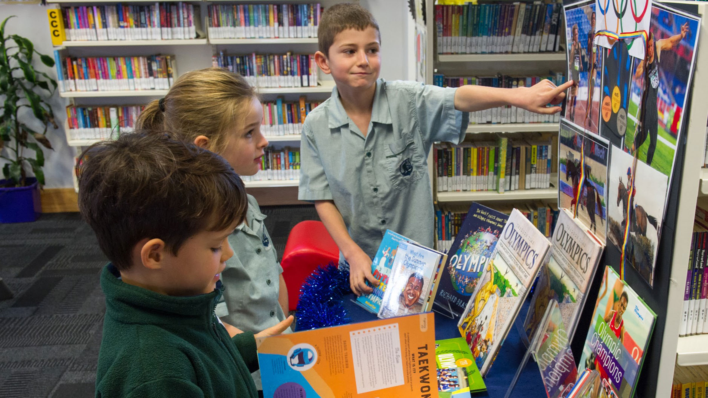 Three children looking at a library display.