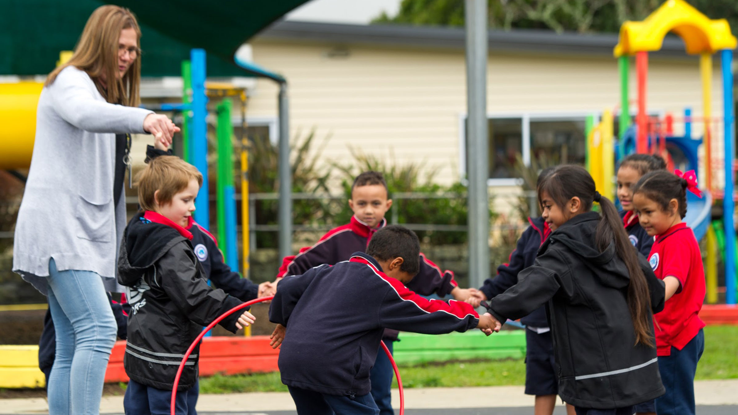 A group of young children playing a game with a hula hoop.