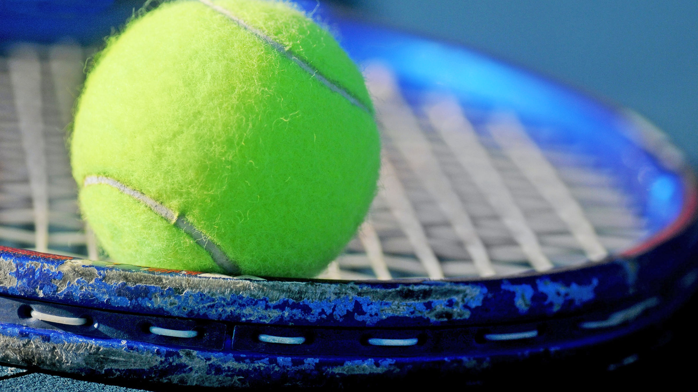 Tennis ball sitting on old tennis racquet