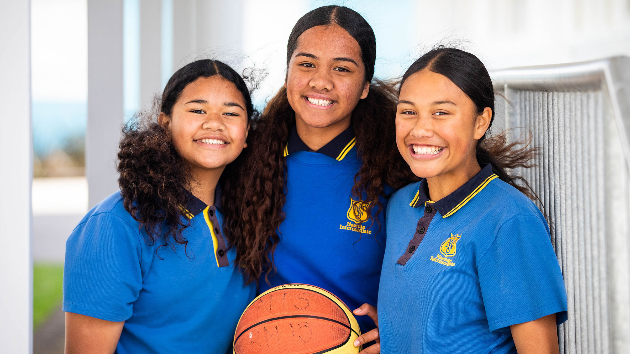 Three teenage girls holding a basketball.
